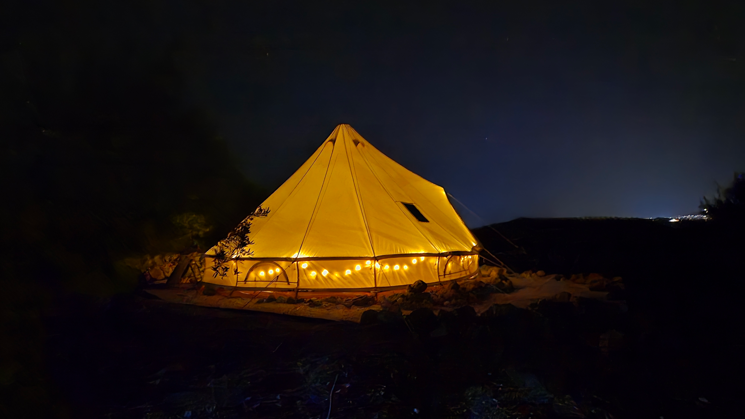 Bell tent glowing with fairy lights at night during a glamping retreat in Sicily